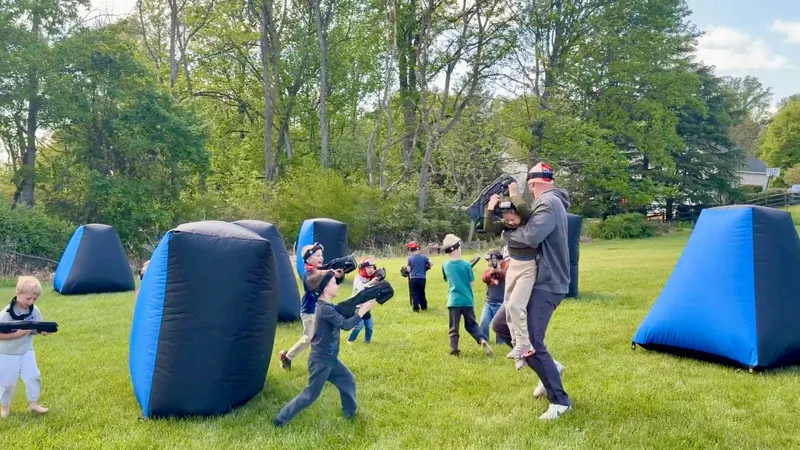 Dad swinging his son mid-game during a backyard mobile laser tag birthday party in Glen Mills, PA